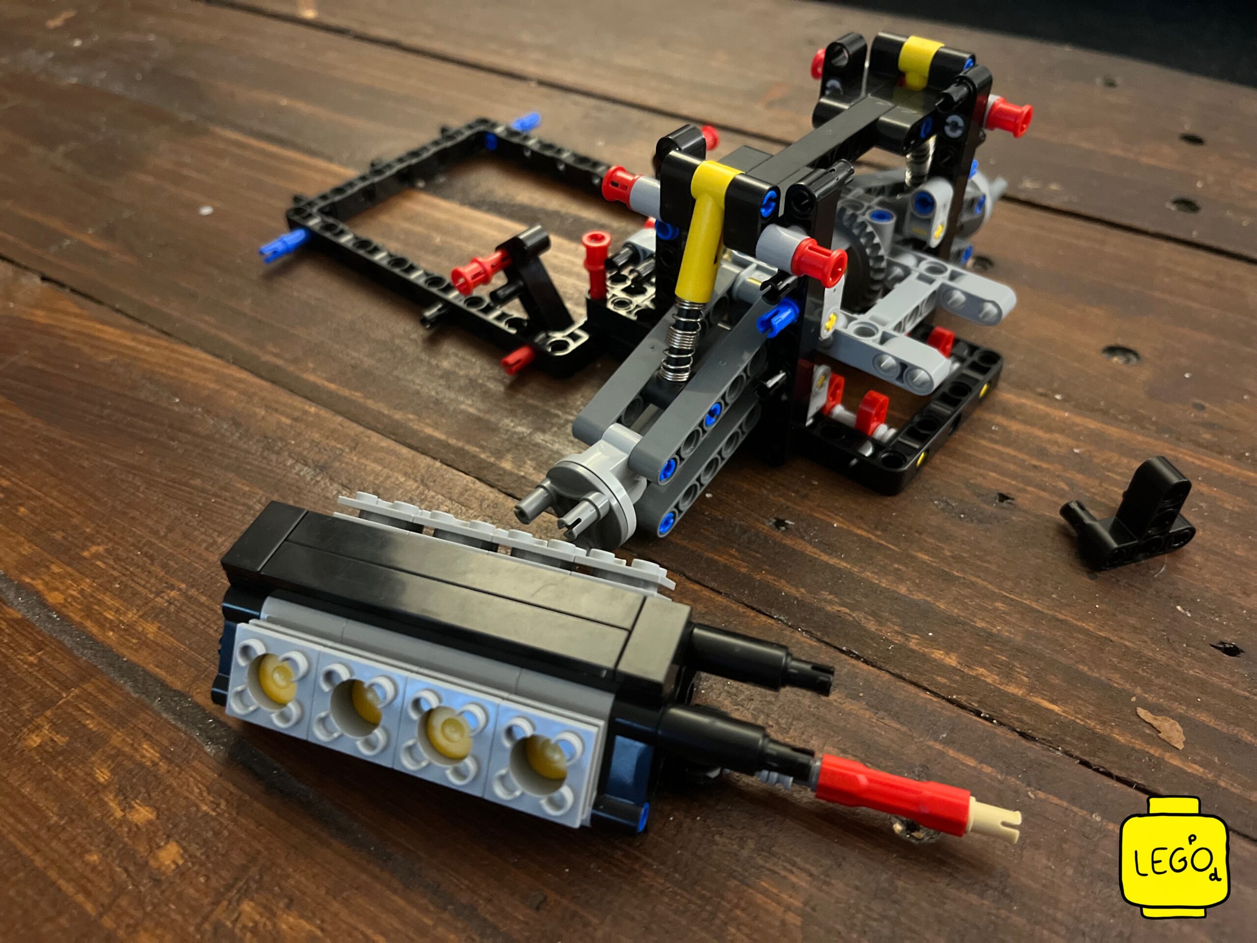 LEGO Technic 42111 Doms Dodge Charger engine sub-assembly and chassis frame side by side on wooden table
