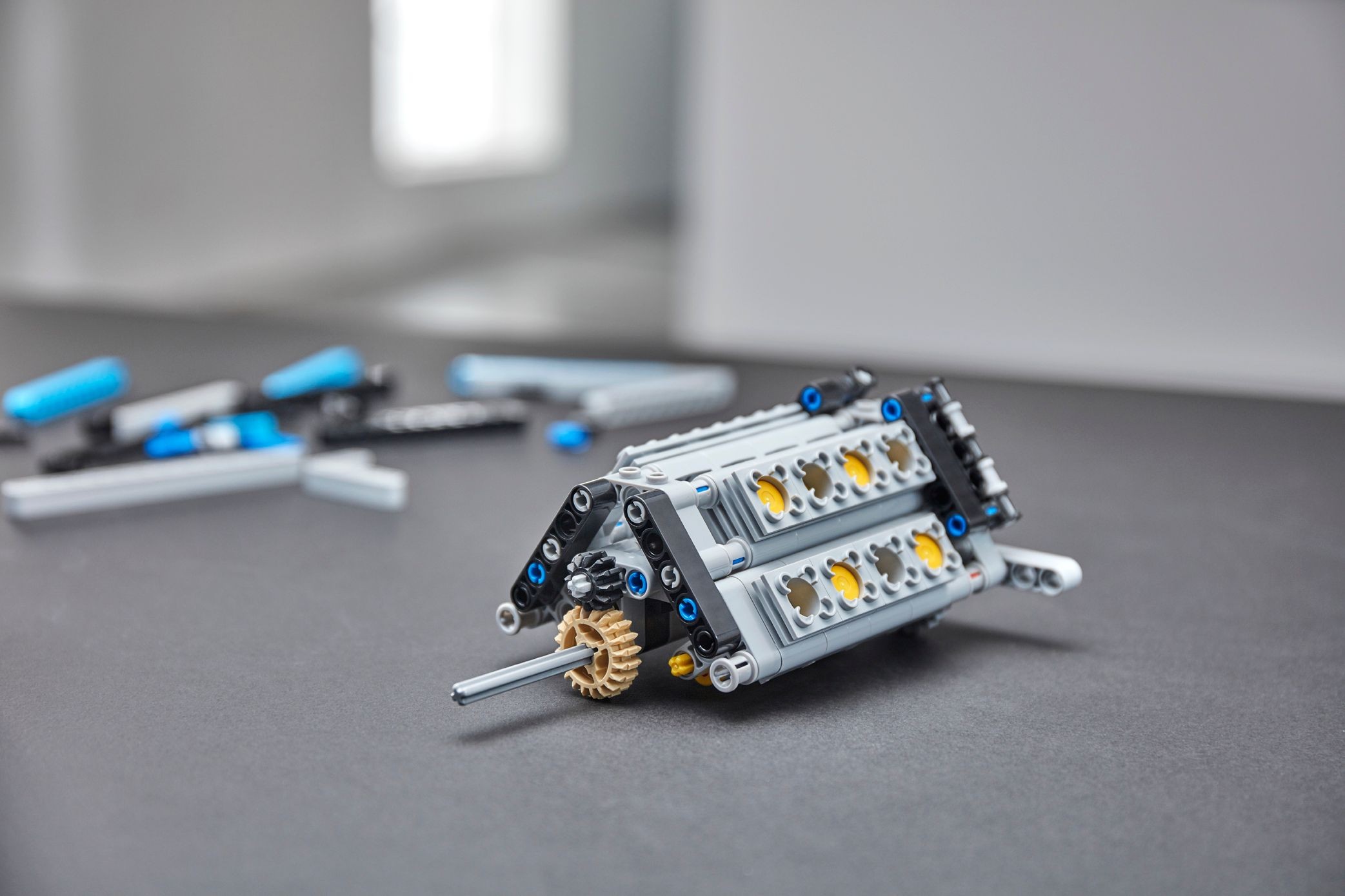 The W16 engine of LEGO Technic Bugatti Chiron (42083) built as a sub-assembly, tan 24-tooth gears at one end, dark azure panels waiting behind it