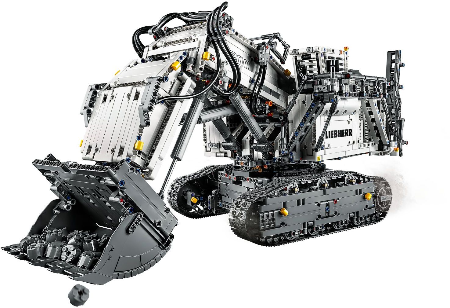 LEGO Technic Liebherr R 9800 Excavator (42100) with the bucket open and full of grey round bricks, the boom raised and black flex tubes running along it, official image