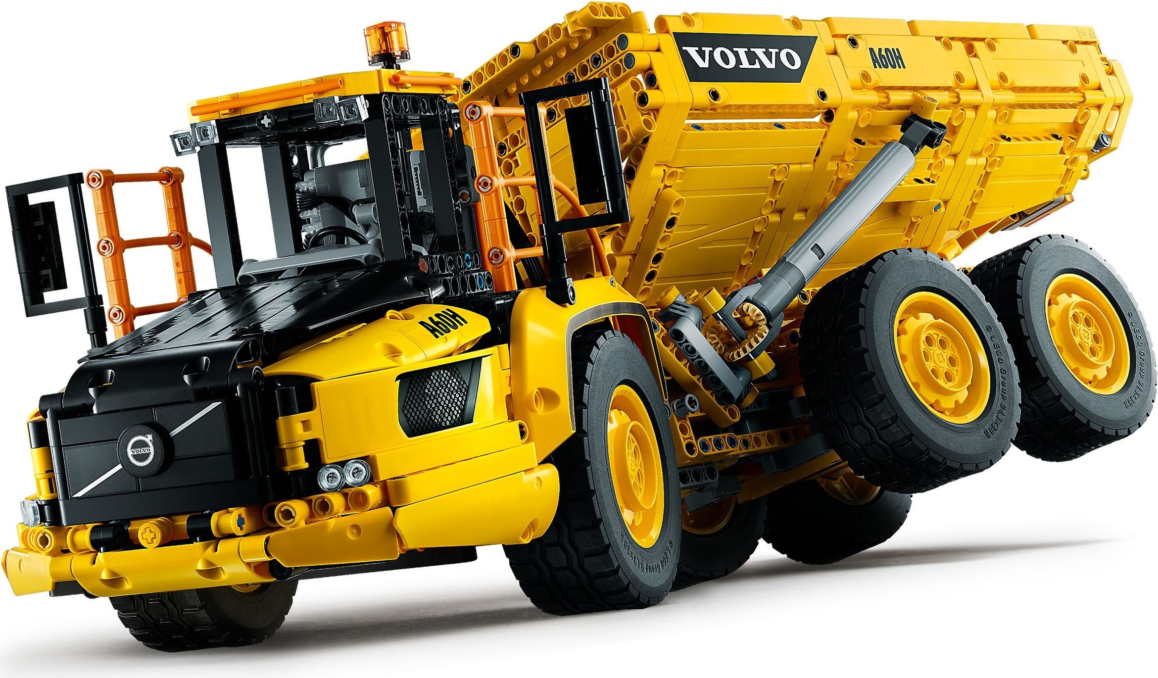 Low front three-quarter view of LEGO Technic 6x6 Volvo Articulated Hauler (42114) showing the black bonnet, orange handrails, mirrors, the grey hub behind the cab and one of the linear actuators beside the bed